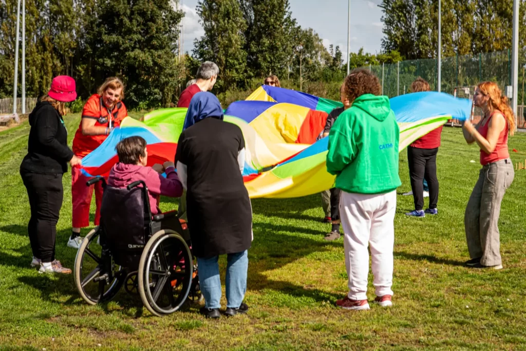 Mensen op een grasveld die een gekleurde parachute omhoog houden