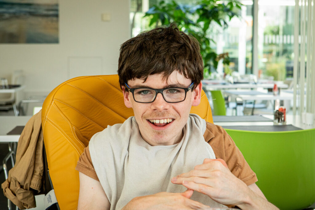 Jongen op gele stoel die lacht naar de camera